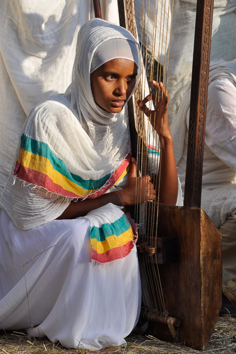 Woman playing large traditional harp-like stringed instrument